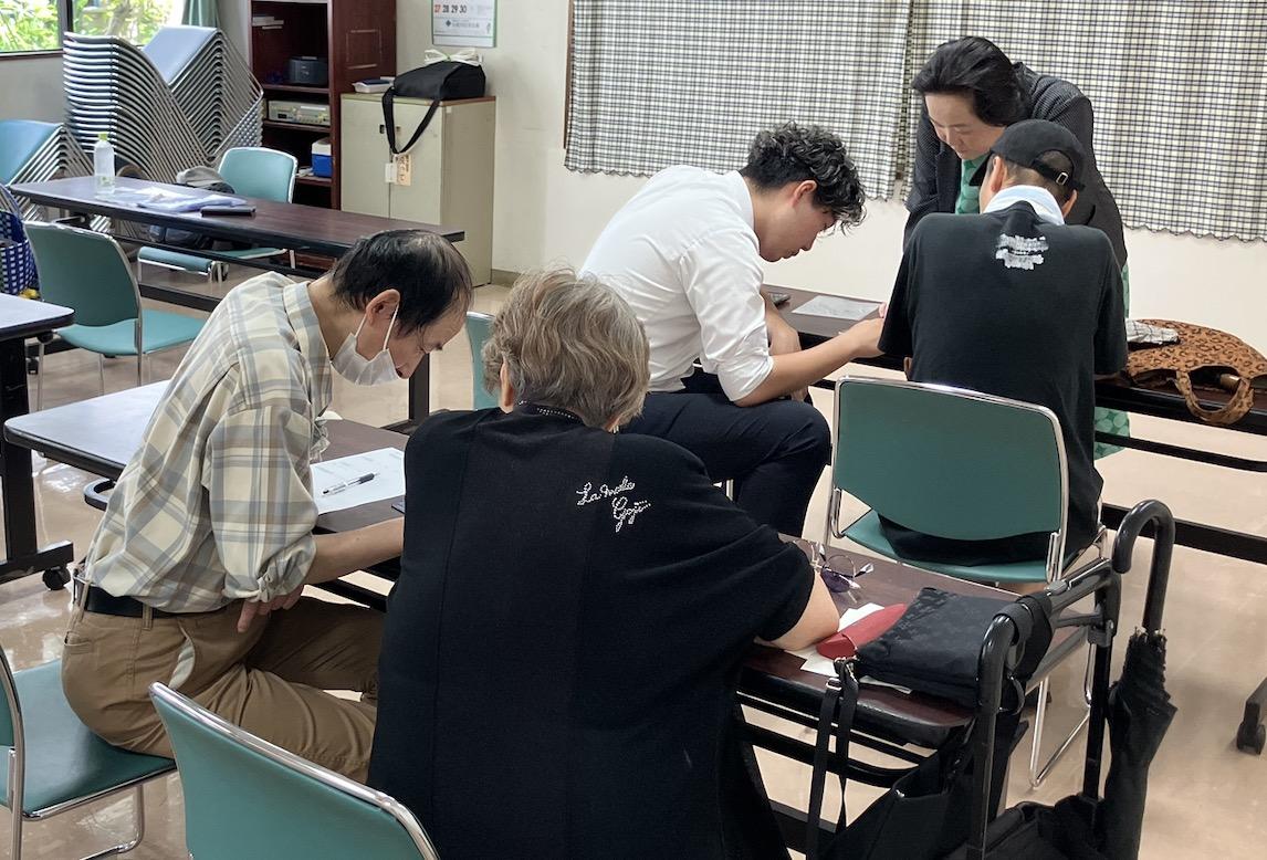 東京アプリの登録のため、スマホと睨めっこする参加者と申請を手伝うボランティアら（2026年9月2日、東京都江戸川区で、弁護士ドットコムニュース撮影）